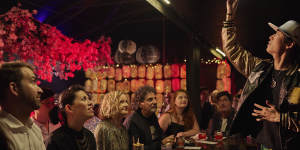 A magician entertains the crowd at the Maho Magic Bar as part of the Sydney Festival.
