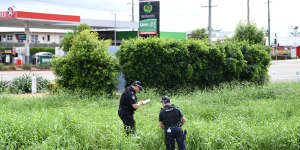 Police examine the scene where two bodies were found in a drain behind the Aitkenvale Library in Townsville.