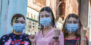 Young women show their inked fingers,a sign they voted in elections in 2020.