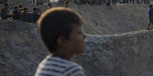 Palestinians look at the destruction after an Israeli airstrike on a crowded tent camp housing Palestinians displaced by the war in Al-Muwasi.