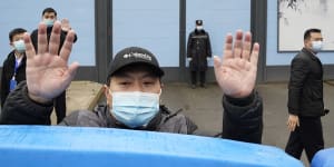 A security guard waves for journalists to clear the road after a convoy carrying the World Health Organisation team entered the Huanan Seafood Market in January 2021.