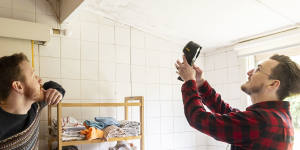 Jordan van den Berg uses a handheld thermometer to check for the source of mould in a renter’s home.