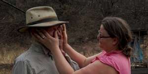 Mark Brooks is comforted by his daughter Kylee on January 9,after returning to the remains of his home near Corryong.