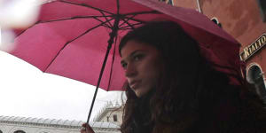 People walk near the Rialto bridge on the occasion of a high tide.