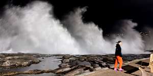 A person walks past large breaking waves at Clovelly beach on Saturday morning. 