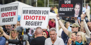Protesters carry signs saying,“We are governed by idiots” before the weekend voting in two western German states.