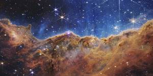 This landscape of “mountains” and “valleys” speckled with glittering stars is actually the edge of a nearby,young,star-forming region in the Carina Nebula,as captured by the James Webb telescope.