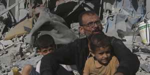 Palestinians sit outside their house following Israeli airstrikes in Rafah refugee camp,southern Gaza Strip,on Thursday.