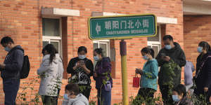 Masked residents line up to receive booster shots against COVID-19 at a vaccination site in Beijing on Monday.