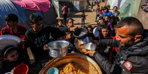 Displaced people line up to receive food in a camp in Rafah,Gaza.