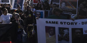 Demonstrators hold placards showing the faces of those who have died in custody.