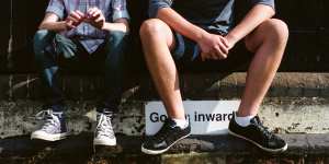 Stock photo of two teenage boys sitting on a wall. 