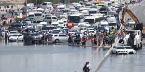 People walk along an flooded highway on April 18 in Dubai.