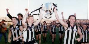 Collingwood players celebrate with the 1990 premiership trophy.