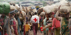 A member of the Red Cross walking among Rwandan Hutus fleeing back to their homeland in 1996 after war broke out in Goma.