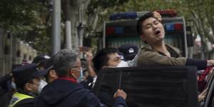 A protester reacts as he is arrested by policemen during a protest on a street in Shanghai,China.