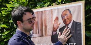 A man poses next to a poster of Silvio Berlusconi outside the former prime minister’s residence in Arcore,near Milan.