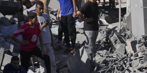 Palestinians look at buildings destroyed in the Israeli bombardment in the morgue in Deir al Balah,Gaza Strip on Tuesday.