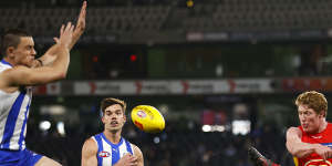 Gold Coast’s Matt Rowell kicks the ball under pressure from Luke Davies-Uniacke.