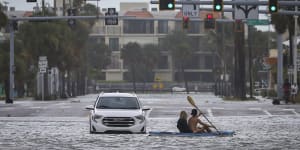 People kayak past an abandoned vehicle in St Pete Beach,Florida.