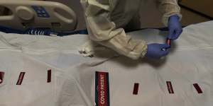 A nurse attaches “COVID Patient” stickers on a body bag of a patient who died of coronavirus in Los Angeles.