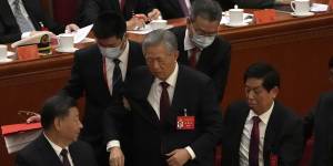 Former Chinese President Hu Jintao,centre,is shuffled away.