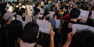 People in Hong Kong hold sheets of blank A4 paper and flowers to protest against COVID-19 restrictions in mainland China.