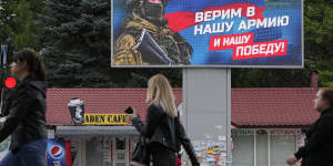 People walk past a billboard displaying a soldier and a Russian flag and reading ‘We believe in our army and our victory’ in Luhansk,Luhansk People’s Republic controlled by Russia-backed separatists,eastern Ukraine.