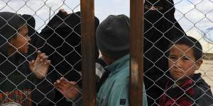 Foreign IS wives and children at the fence line of the foreign section of Al Hawl camp in Syria.