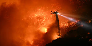 A fire fighting helicopter drops water near the Mandeville Canyon neighbourhood and Encino.