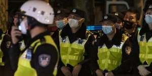 Police officers stand guard during a protest in Shanghai on Sunday night.