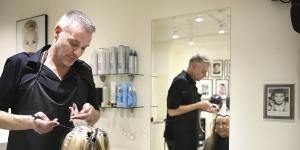Russell James attends to the locks of client in his Sydney CBD salon.