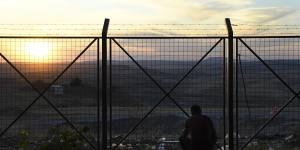 A refugee who has fled Syria into Iraqi Kurdistan looks towards his homeland as the sun sets on the holding centre for undocumented refugees.