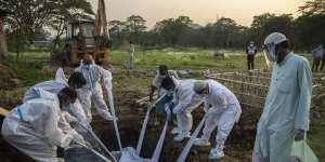 Relatives and municipal workers in protective suits bury the body of a COVID-19 victim in Gauhati,India.