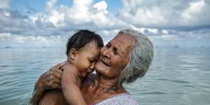 Suega Apelu bathes a child in a lagoon in Tuvalu,one of the Pacific Island nations most threatened by climate change.