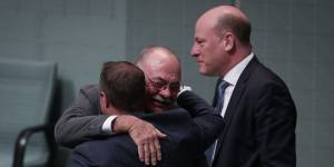 Government gay marriage supporters Tim Wilson and Warren Entsch embrace as Trent Zimmerman watches on.