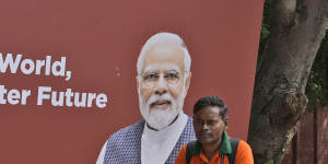 A para-military force soldier stands guard in front of a G20 banner with the photograph of Indian prime minister Narendra Modi. 
