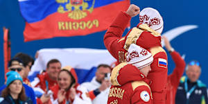 Gold medallist Anastasiia Bagiian of Team Russia and guide Sergei Siniakin celebrate to their team as they make their way to the podium during the medal ceremony for the Women’s 10km Para Cross-Country Skiing Vision Impaired race.