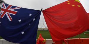 Parliament House is seen behind an Australian and a Chinese flag 