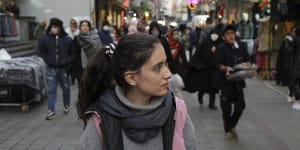 A woman walks around a commercial district without wearing her mandatory Islamic headscarf in downtown Tehran.