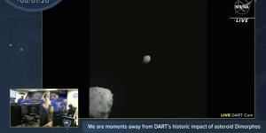 An image from the NASA livestream shows the DART spacecraft close in on the white speck of asteroid Dimorphos while passing the larger asteroid Didymos. 