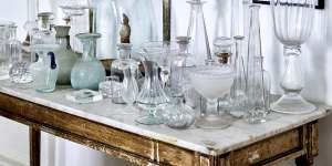 An antique,marble-topped French table displays a collection of Collison’s glassware. Above it are works by artists including Lee Miller and Max Dupain.