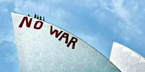 Cleaners attempt to remove the No War slogan painted on the Opera House by anti-war protesters in 2003.