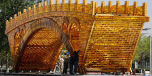 Workers install wires on a'Golden Bridge of Silk Road'structure on a platform outside the National Convention Centre in Beijing.