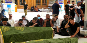 Mourners pray near the coffins of coronavirus patients who were killed in a hospital fire,in Najaf,Iraq.