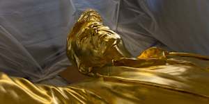 The golden Trump statues rests beneath its protective tent. 