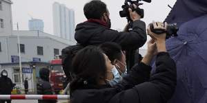 A plainclothes security person uses his umbrella to block journalists from filming after the World Health Organisation team arrive at the Baishazhou wholesale market on the third day of field visit in Wuhan in central China’s Hubei province on Sunday,January 31.