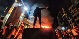 An Iranian woman stands defiantly above her burning headscarf.