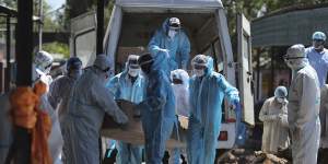 Health workers and relatives carry the body of a COVID-19 victim for cremation in Jammu,India. 