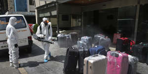 A worker sprays disinfectant on luggage outside a hotel in Beirut. 